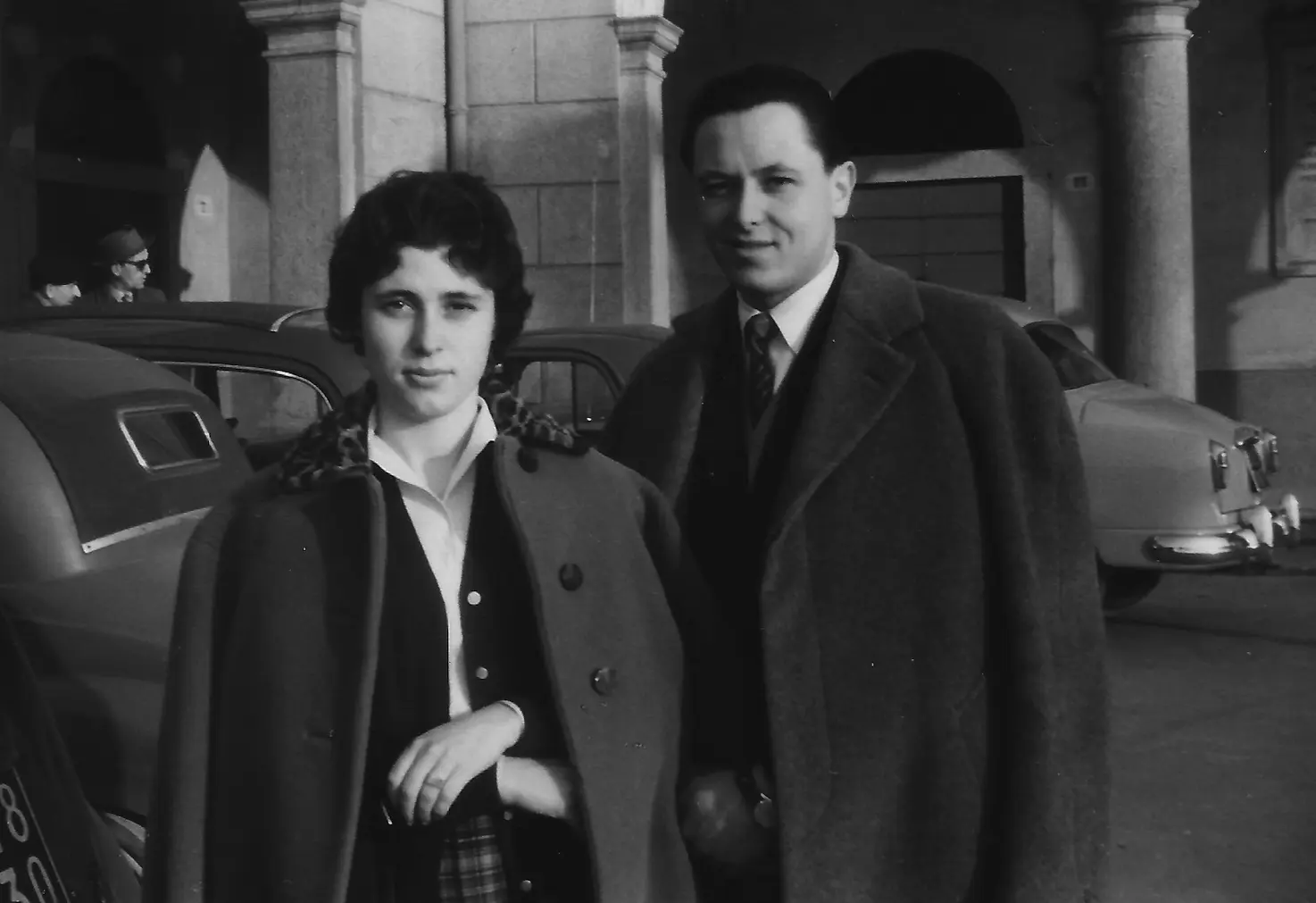 Etta e Diego giovani, in cappotto, accanto a un'automobile a Laveno nel 1956